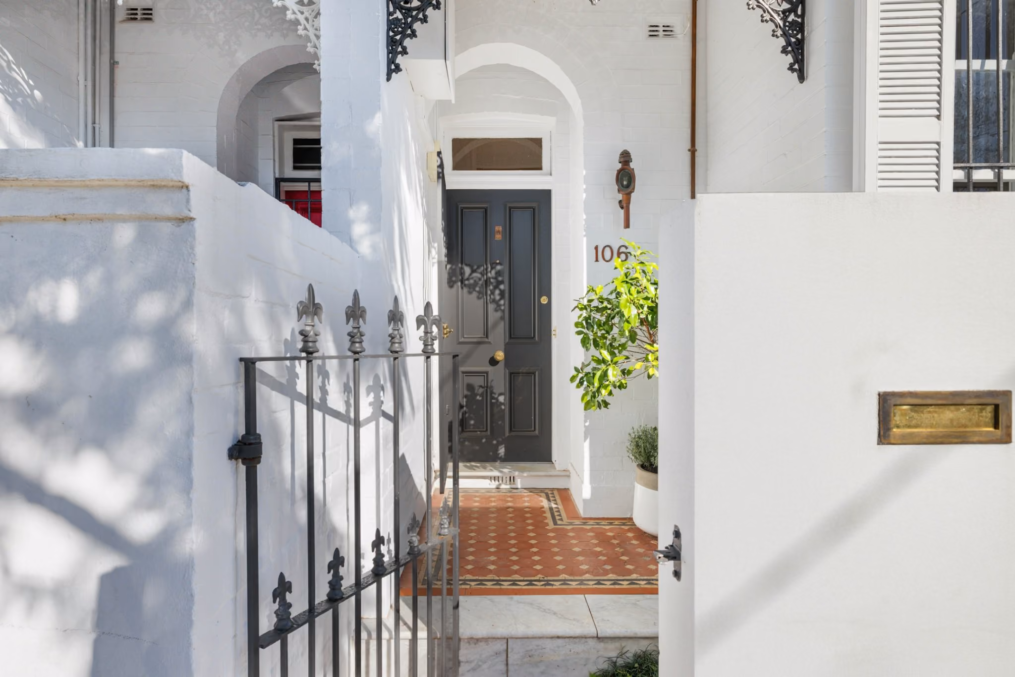 Restored Edwardian terrace entry in Woollahra featuring tessellated tiles, white rendered brickwork and charcoal heritage door.