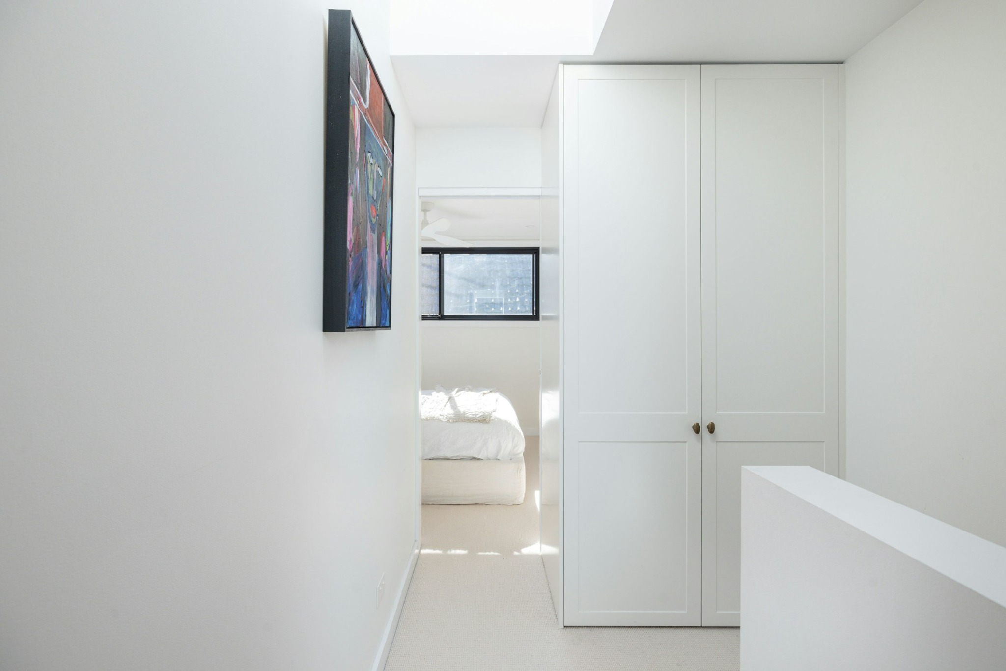 Minimal upper-level hallway with skylight, custom joinery and filtered natural light.
