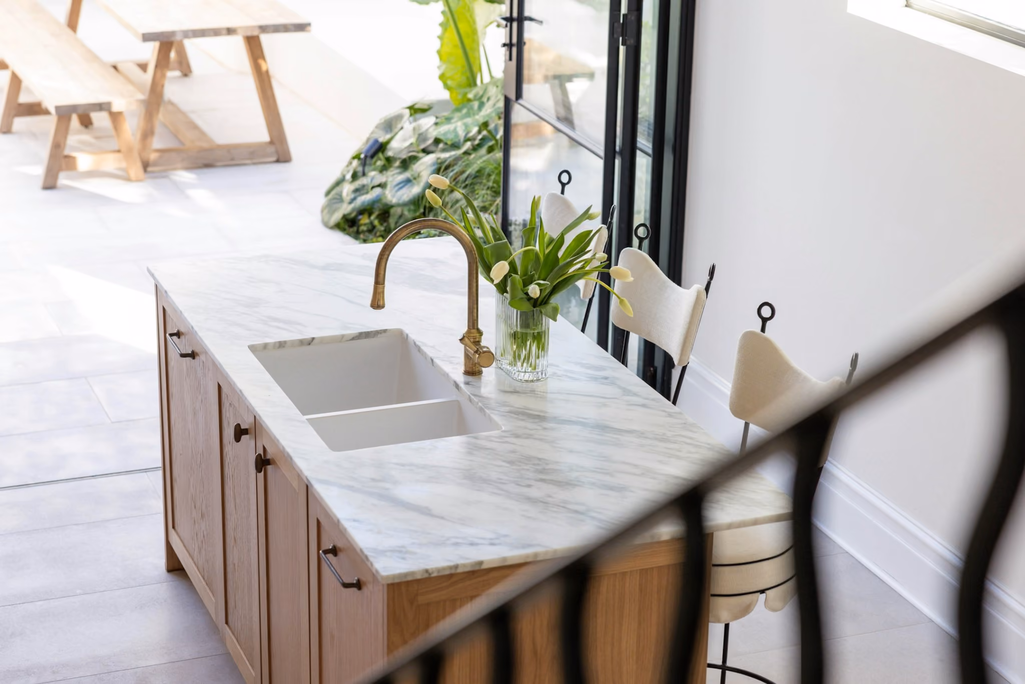 Marble kitchen island with brass tapware overlooking landscaped courtyard in Woollahra terrace renovation.