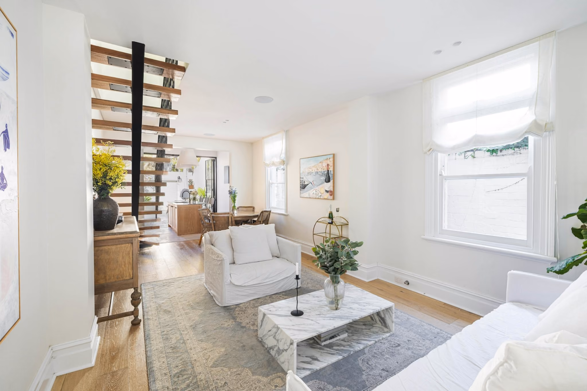 Open living and dining spaces connected to rear kitchen extension in renovated heritage terrace house.