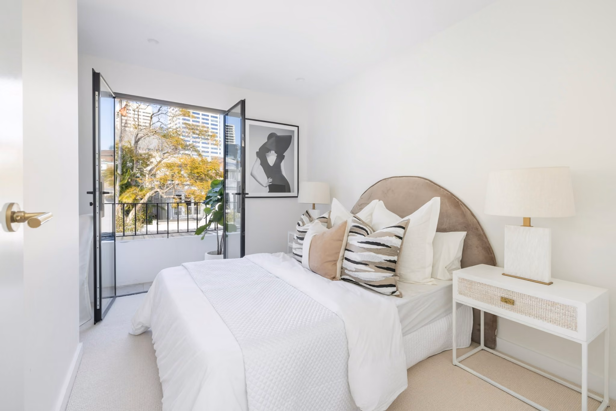 Minimal main bedroom opening to balcony within contemporary upper-level addition to heritage terrace.
