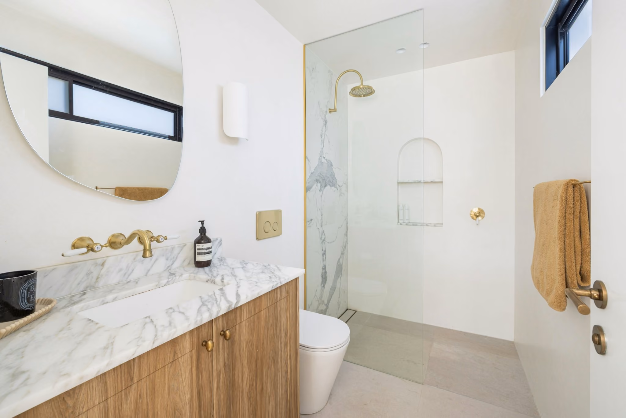 Contemporary ensuite bathroom with marble vanity, brass tapware and frameless walk-in shower.