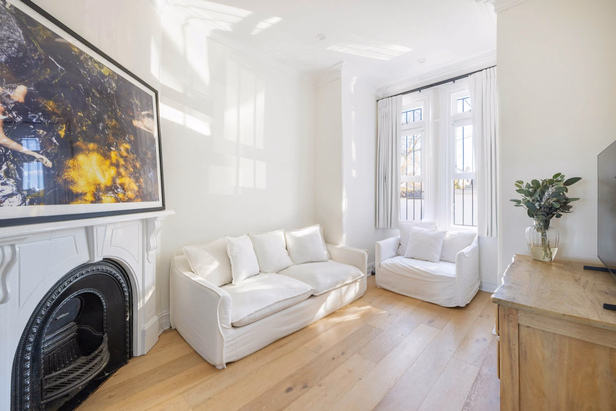 Restored heritage living room with original fireplace, soft natural light and contemporary furnishings.