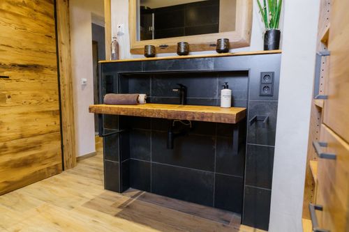 Rustikales Badezimmer-Design mit Holz-Waschtisch und schwarzen Fliesen