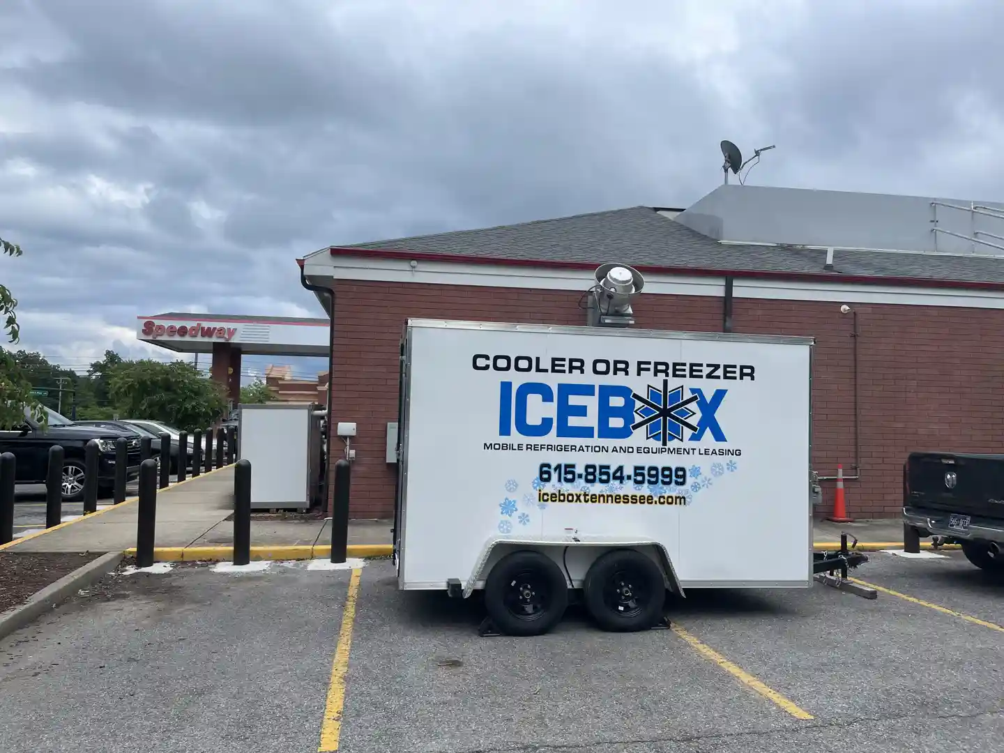 a clean, modern refrigerated trailer parked neatly behind a busy restaurant, with catering staff loading items - extra freezer space