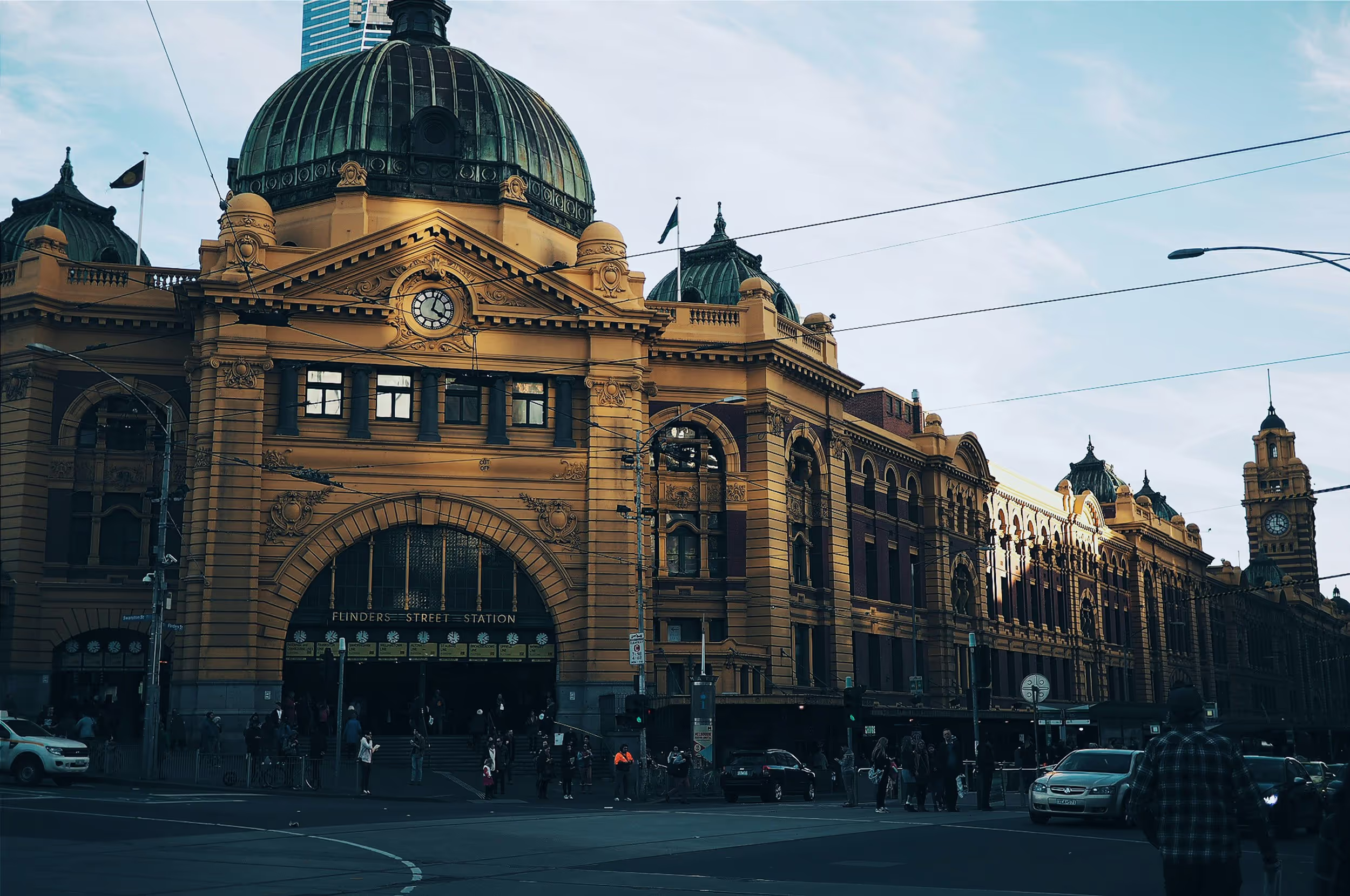 Exterior view of Flinders Street Station in Melbourne with its yellow facade and clock tower under a clear sky.