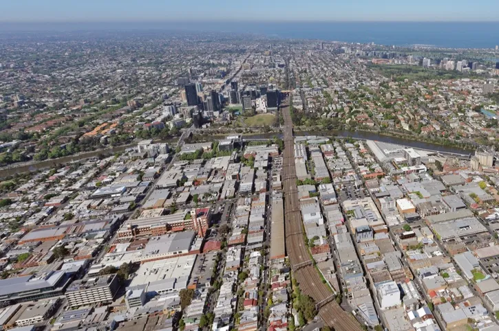 Aerial view of an urban area with a railway running through the middle, surrounded by residential and commercial buildings.