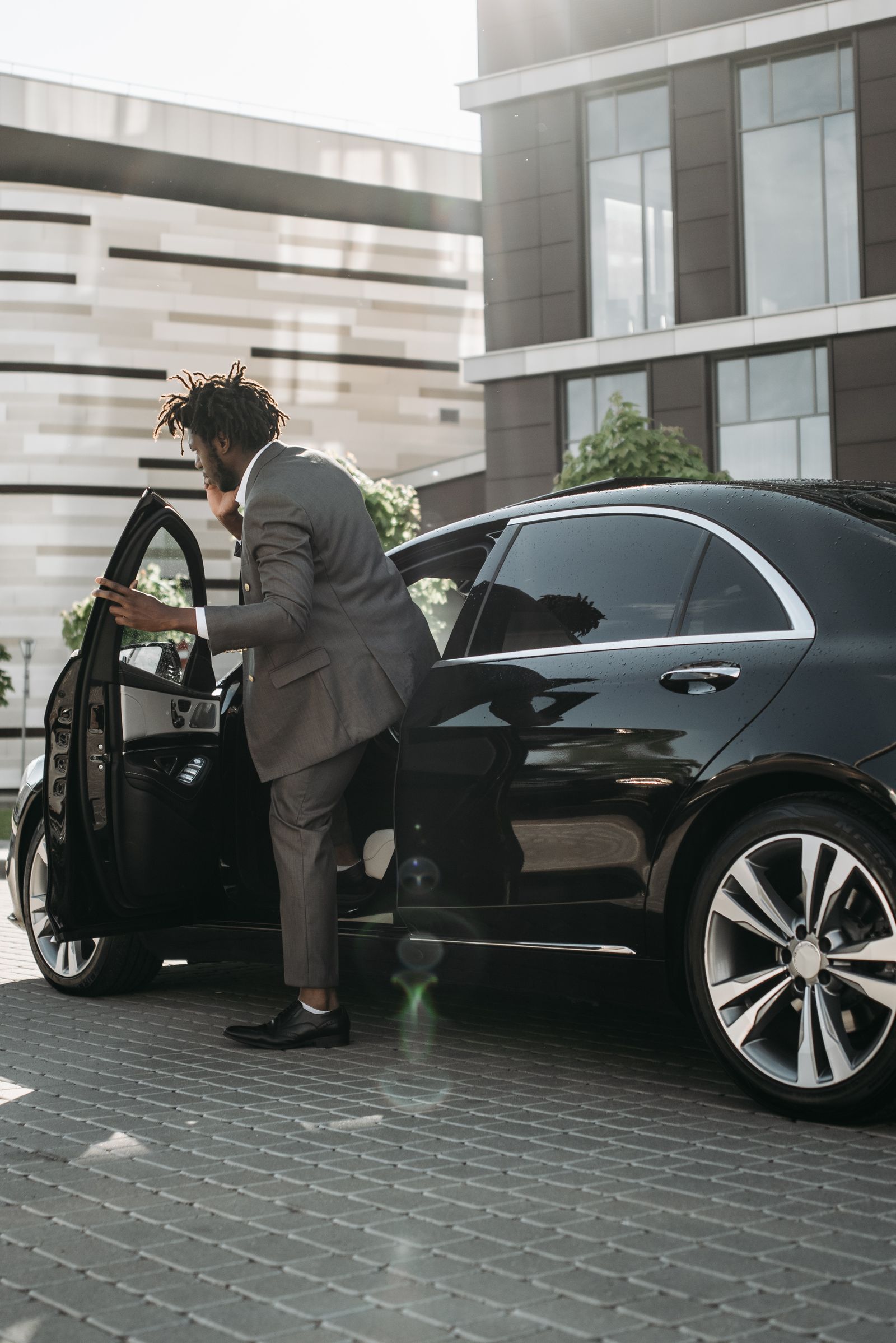 Executive stepping into a black chauffeur car