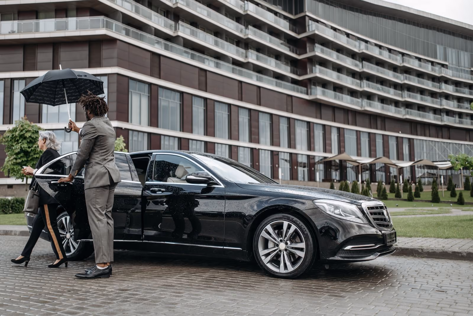 Executive stepping into a black chauffeur car