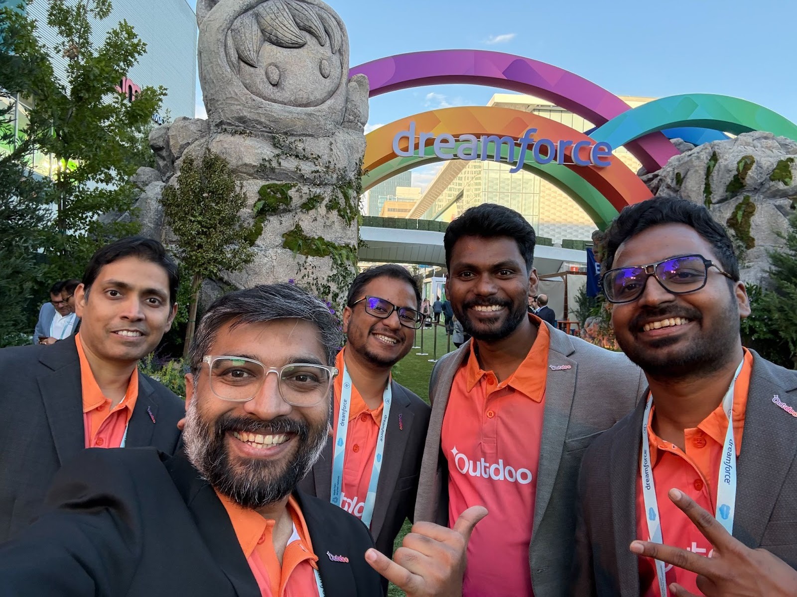 Outdoo AI team at Dreamforce 2025 posing in front of the Dreamforce entrance arch, representing the brand in matching orange shirts and blazers.