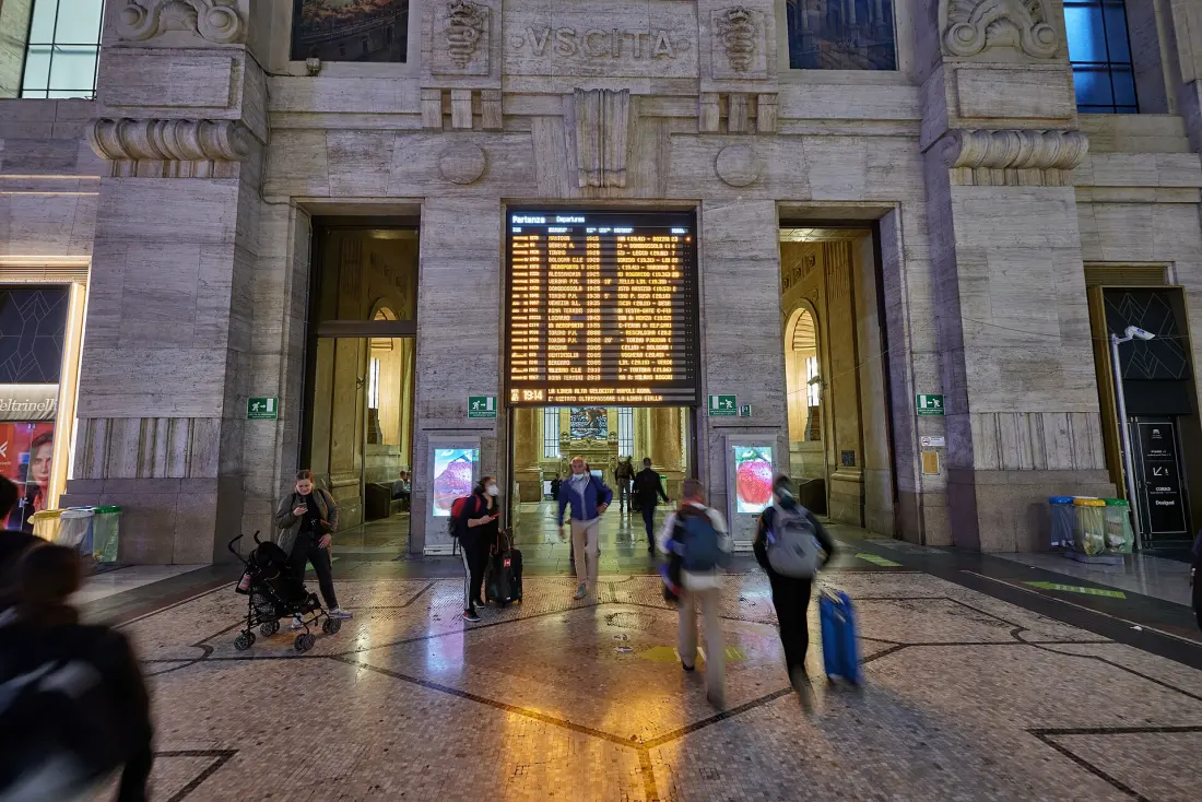 Viaggiatori sotto il tabellone delle partenze della Stazione Centrale di Milano