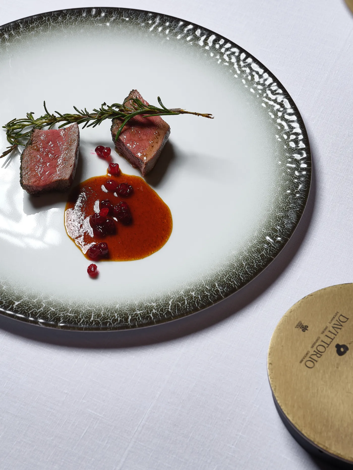Un piatto di Da Vittorio: filetto con salsa e ribes, servito su una tovaglia di lino bianco