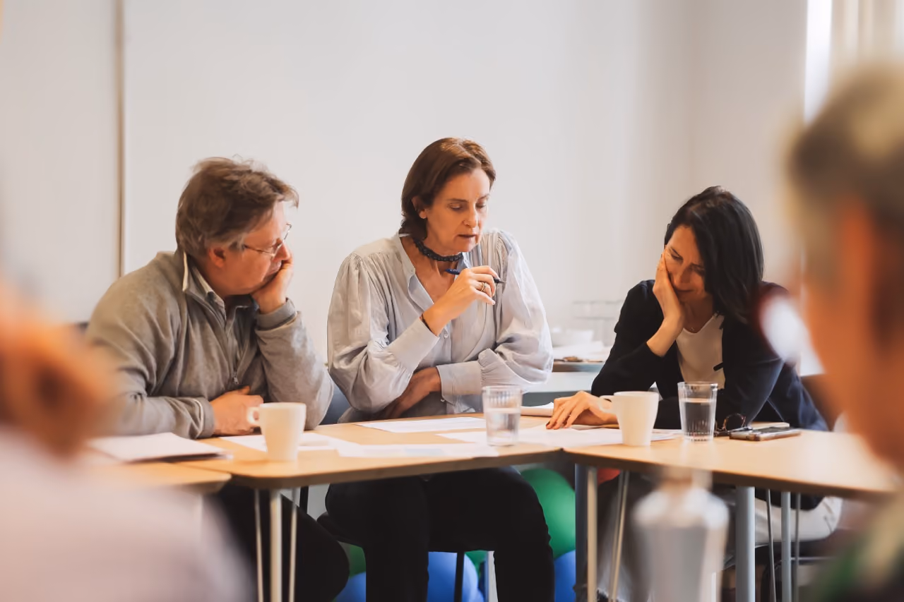 Trois seniors discutent autour d'une table pendant une formation.
