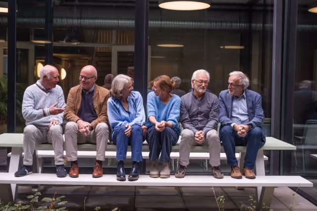 Groupe de seniors assis sur un banc qui sourient et se regardent
