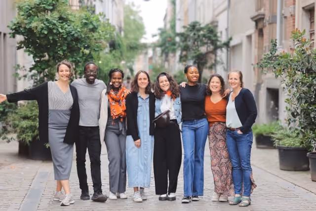 Groupe de 8 personnes posant dans une rue avec des profils et des âges différents qui sourient au photographe 