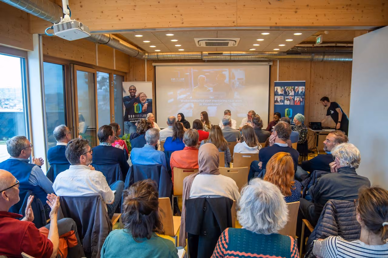 Pièce remplie de personnes assises qui écoutent un panel d'invité lors d'un évènement organisé par DUO for a JOB pour sensibiliser.