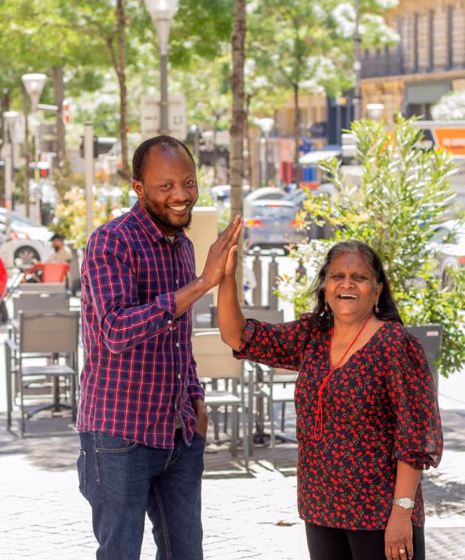 un jeune homme noir tapant dans la main d'une dame plus âgée au teint hâlé en souriant