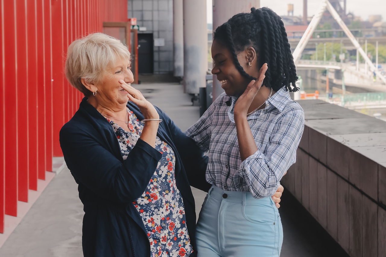Une jeune femme noire et sa mentor une femme d'une cinquantaine d'années aux cheveux blonds sourient en regardant un ordinateur portable ouvert