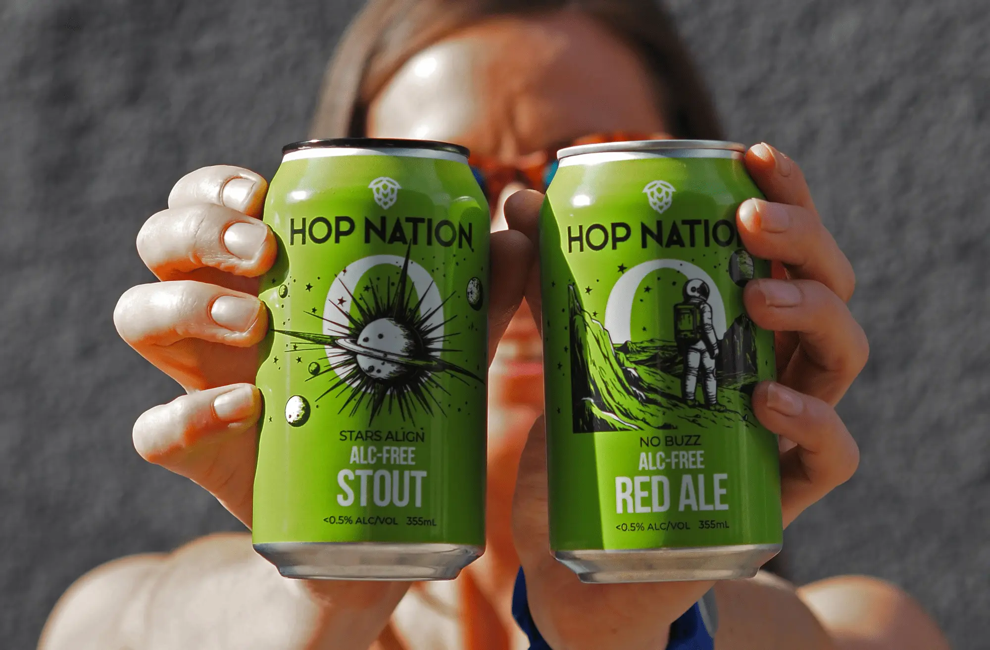 A person holding two cans of Hop Nation's stout and red ale.
