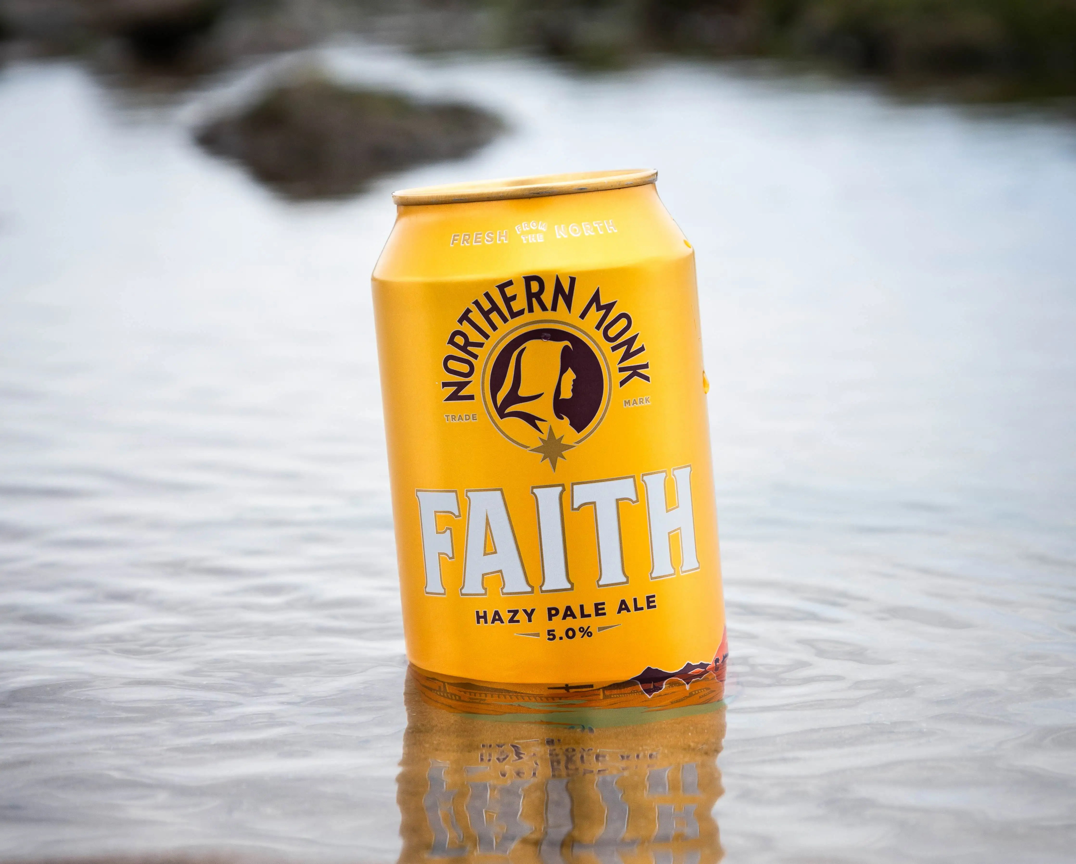 Northern Monk Faith Hazy Pale Ale can resting in water, highlighting its connection to nature and sustainability.