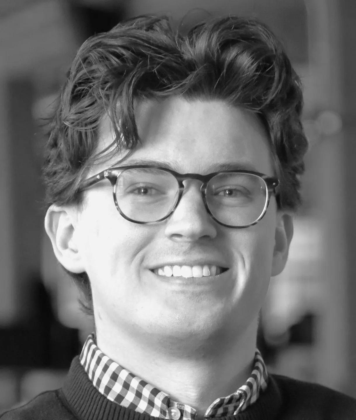 Black and white picture of a man with glasses smiling for a picture