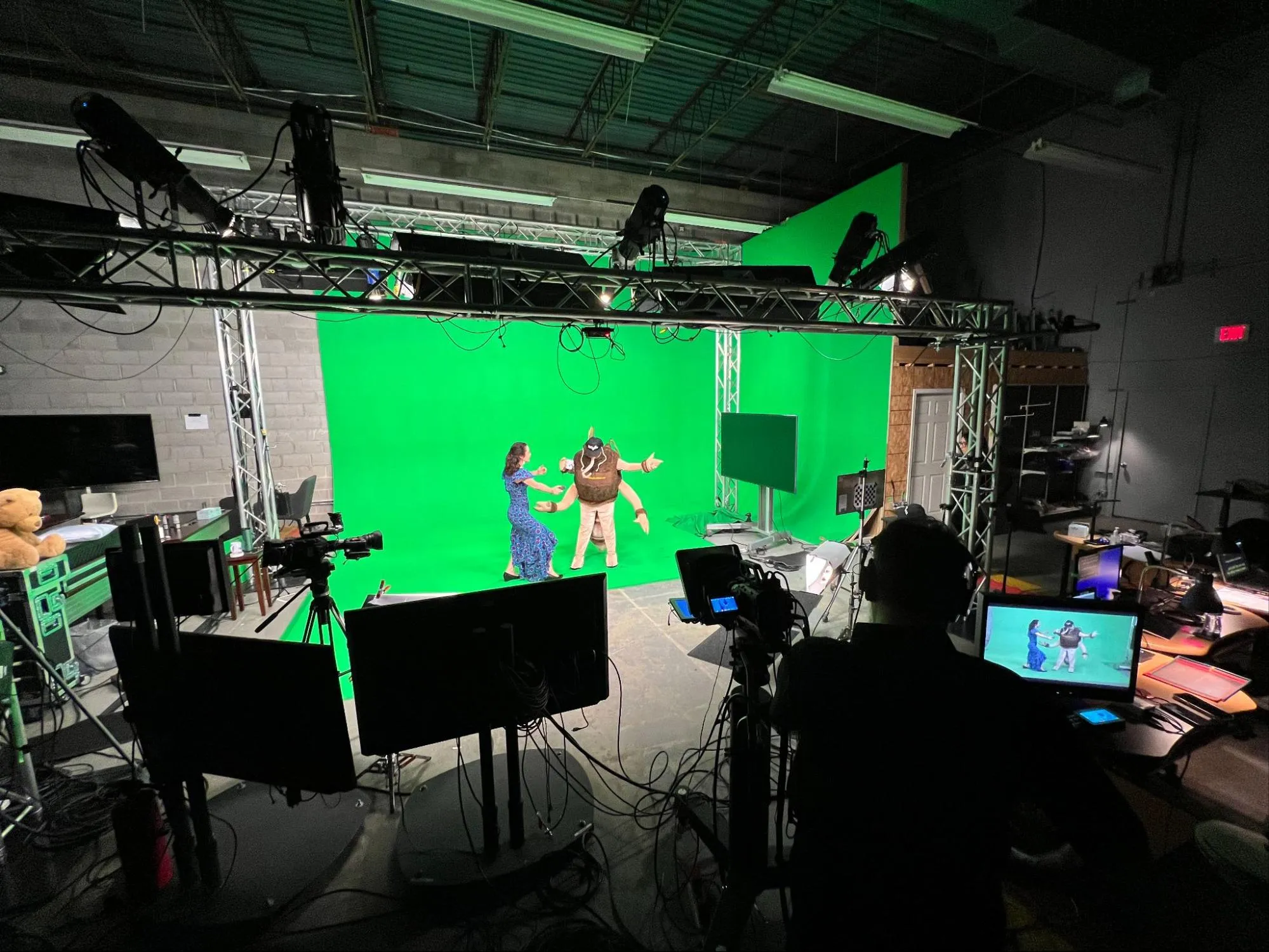 Two people filming a video behind a green screen