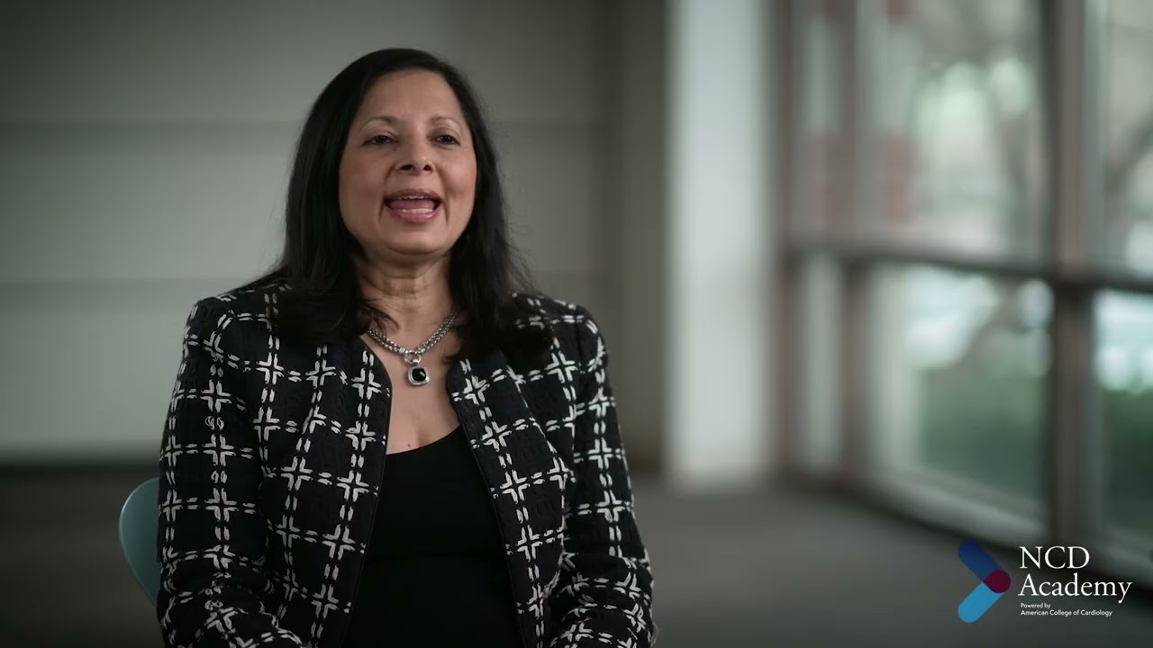 Woman with long dark hair in a black and white tweed jacket speaking during an NCD Academy interview on the road to health equity