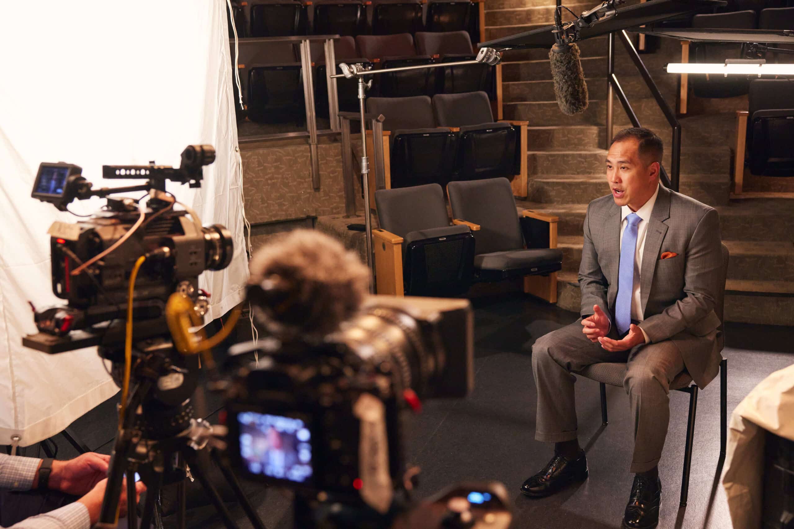 Professional cinema camera filming a man in a suit seated for an interview in an empty theater
