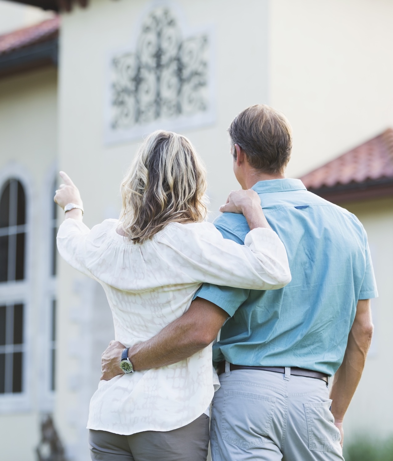 Couple standing in front of a house with the women pointing