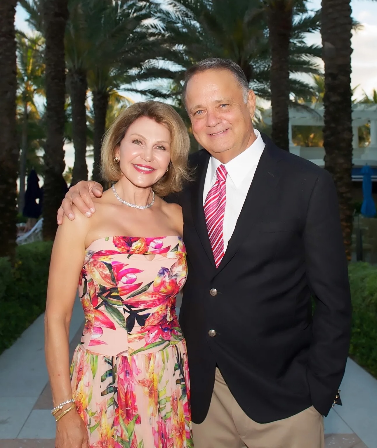 A man and woman smiling together outdoors at a tropical resort