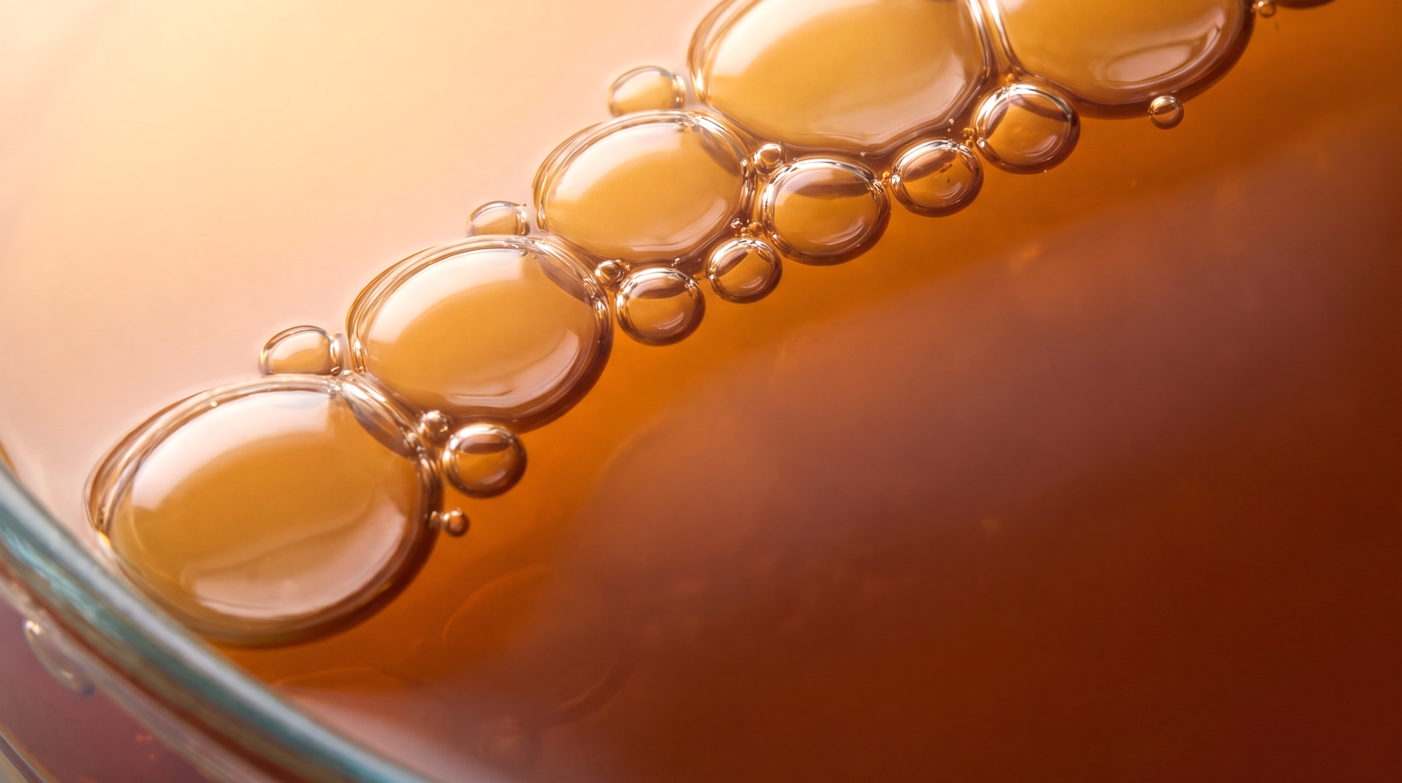 A close-up image showing a series of bubbles rising in a golden-brown liquid.