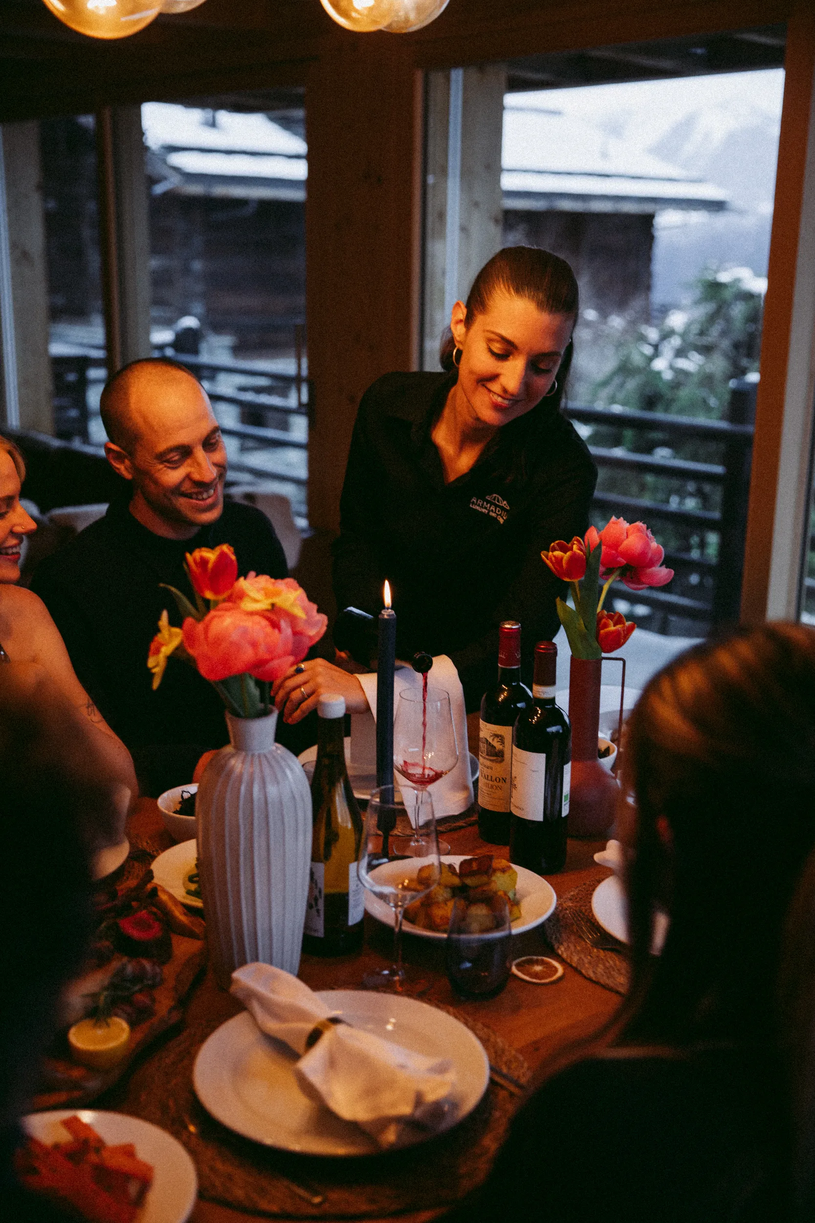 An Armadillo host serves guests at a candlelit dinner in a luxury catered ski chalet in Verbier