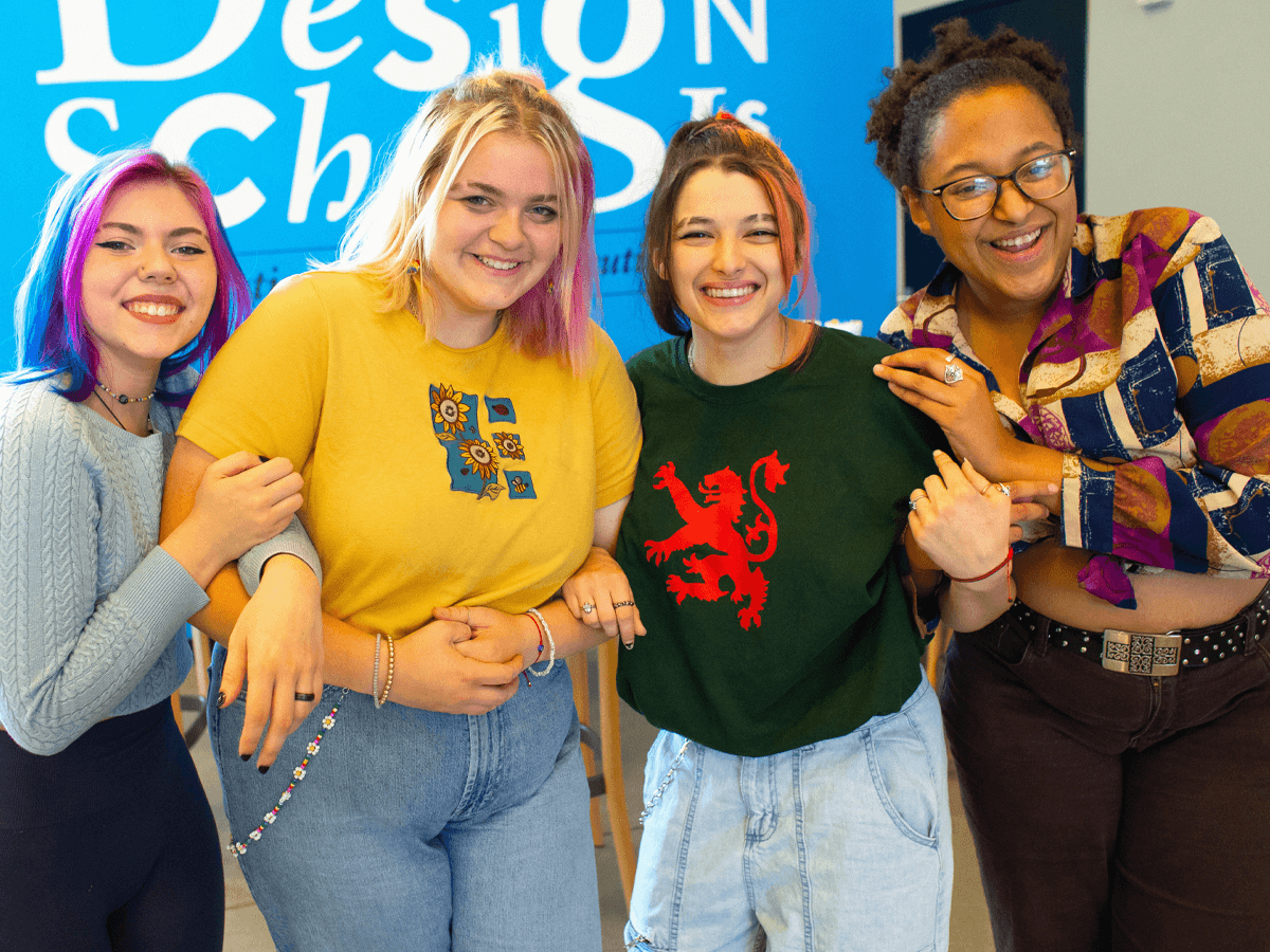 4 smiling female students holding each other's arms.