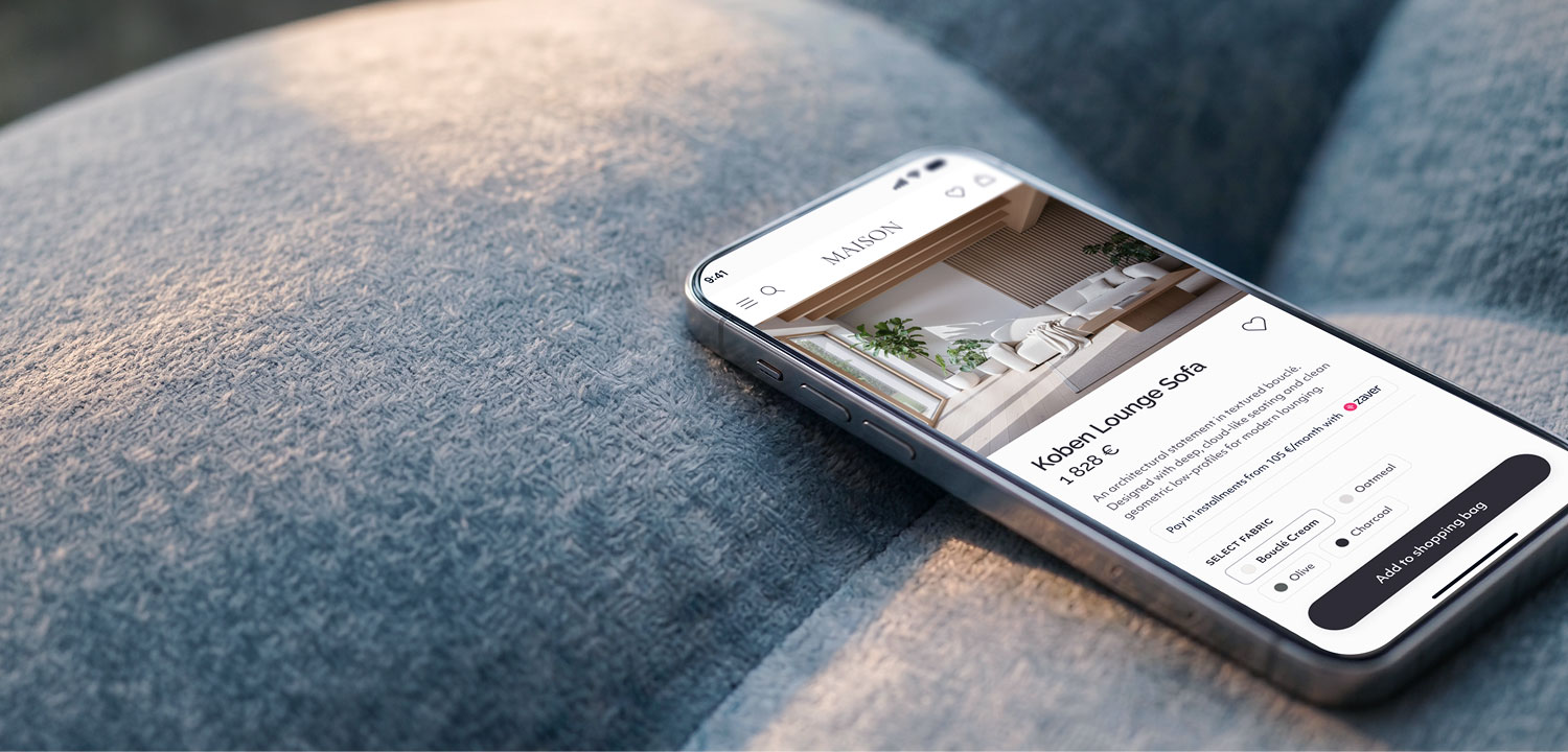 Smartphone on gray fabric showing online store page for Koben Lounge Sofa with options and add to bag button.