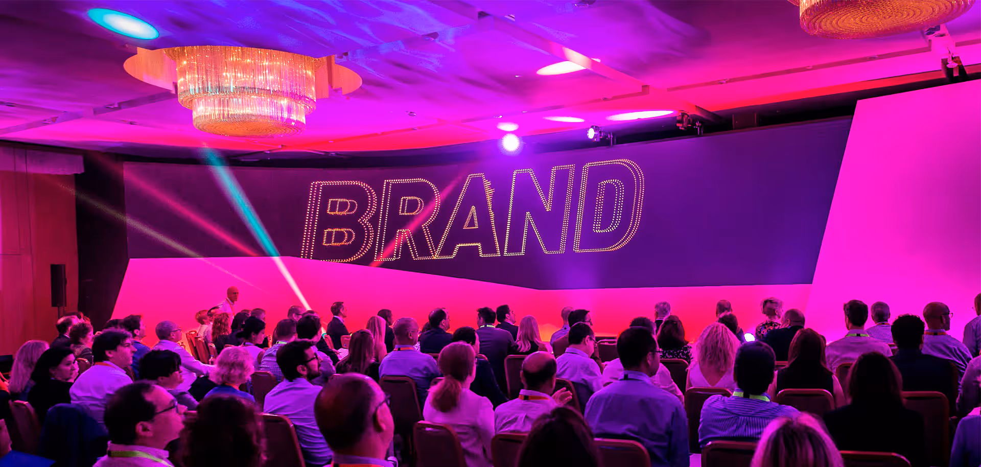 Business audience seated with word BRAND large on screen.