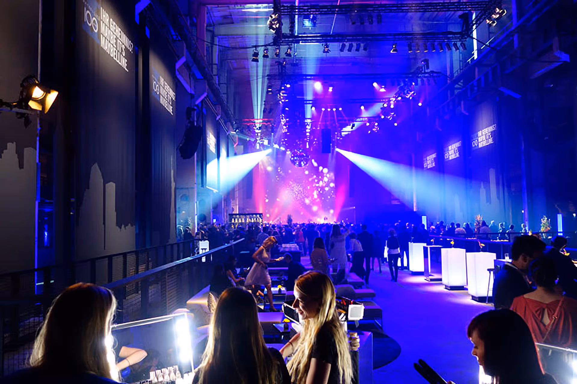 Standing audience at corporate event watch dramatic live show.