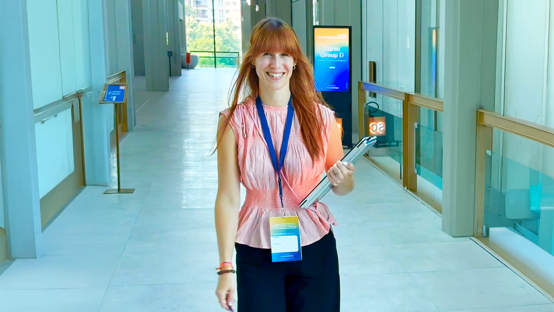 Event professional smiling on stage in front of large screen.
