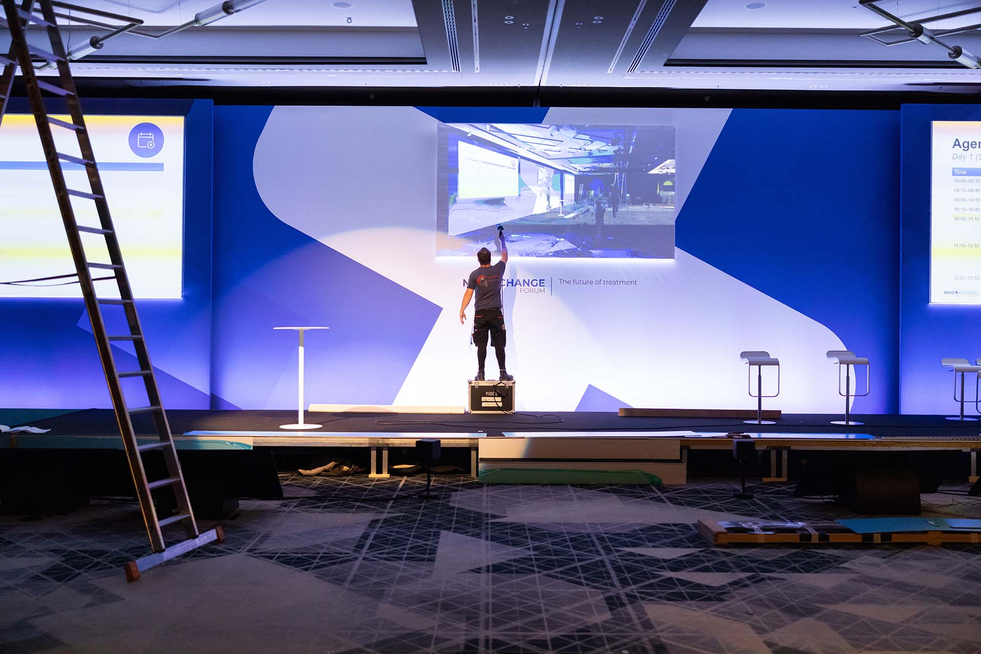 Crew member touches up screen behind stage as image projected from behind.