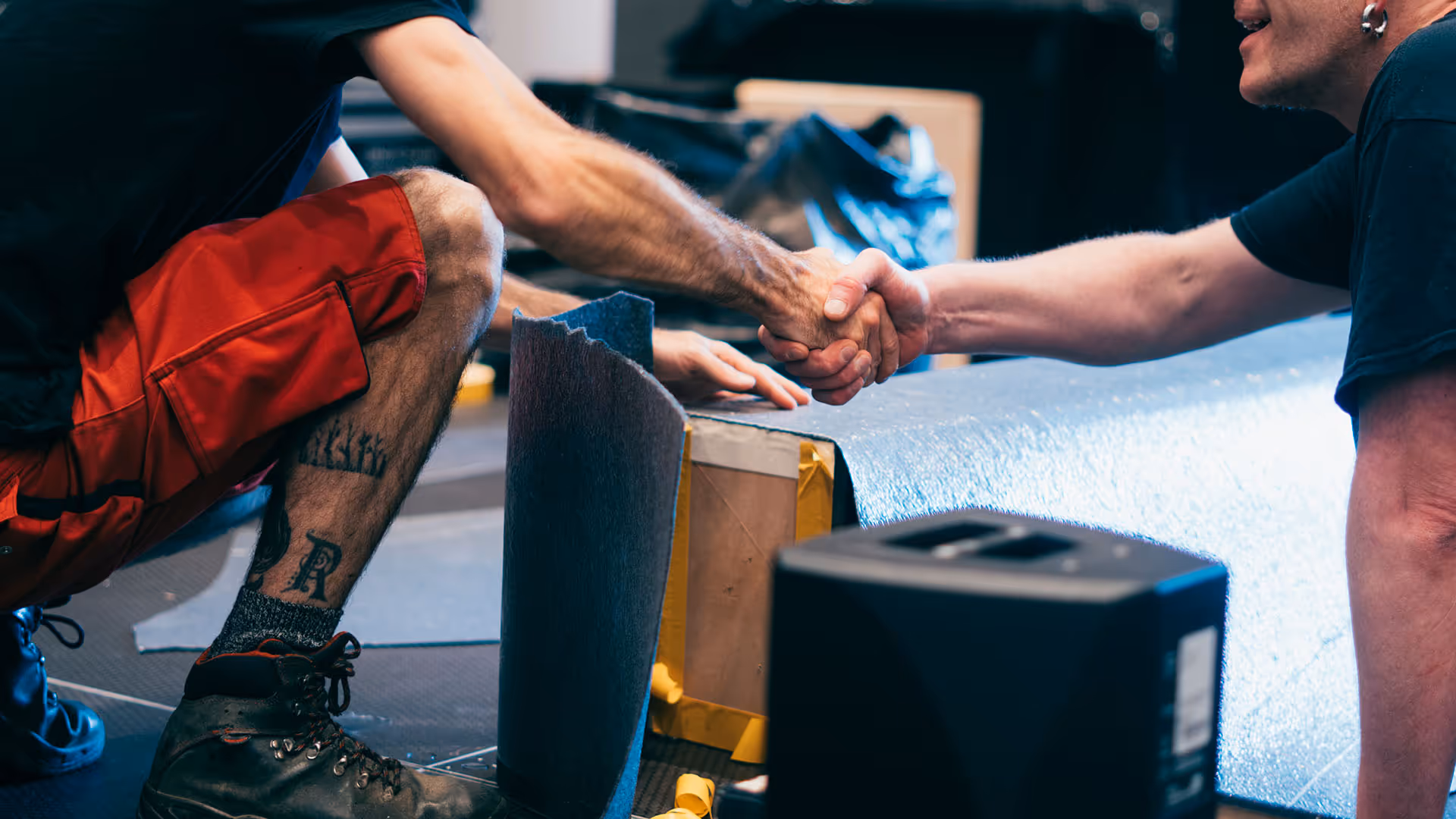 Close up of two crew members shaking hands before working on stage build.