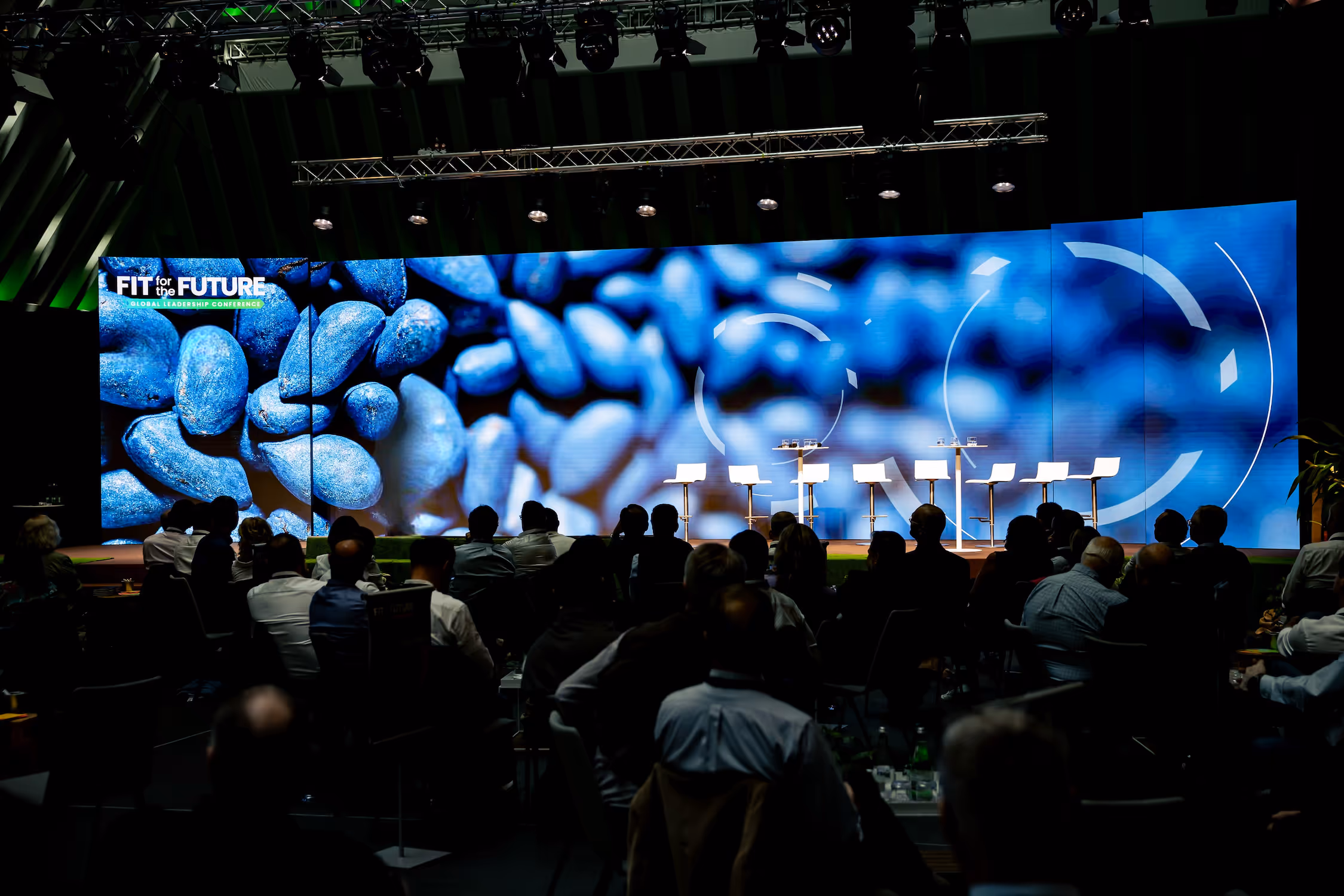 Stage at corporate meeting set up for panel discussion with high stools.