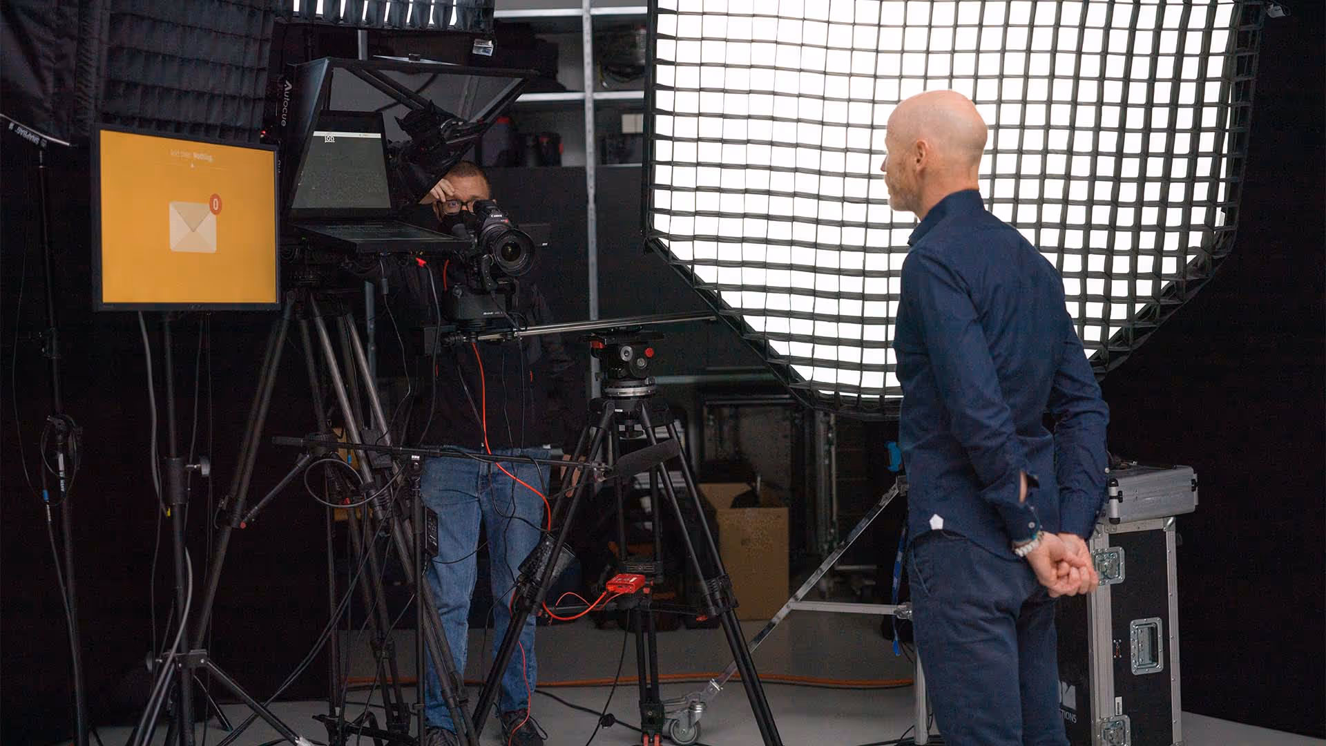 Presenter and cameraman in studio with lights during final setup.