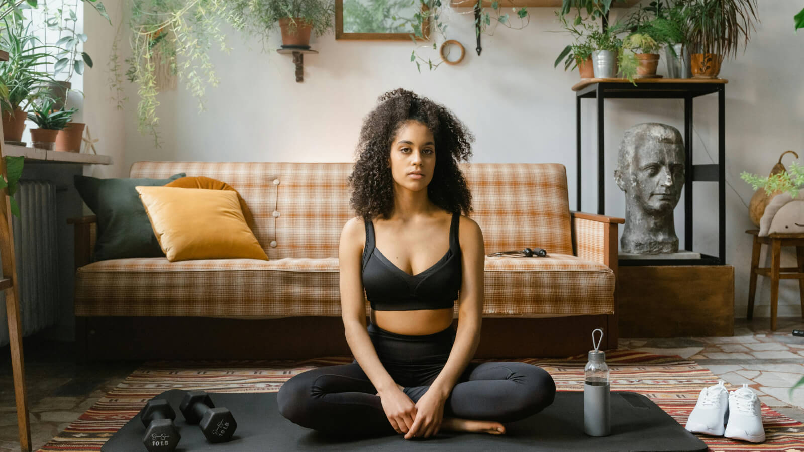 young woman sat on a yoga mat in her living room