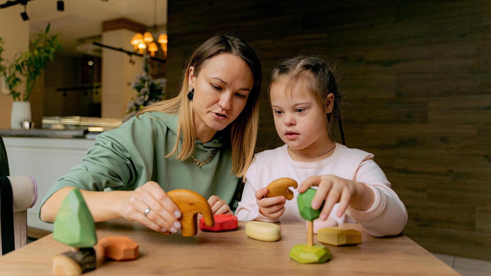 Mum and disabled child playing with wooden shapes and blocks