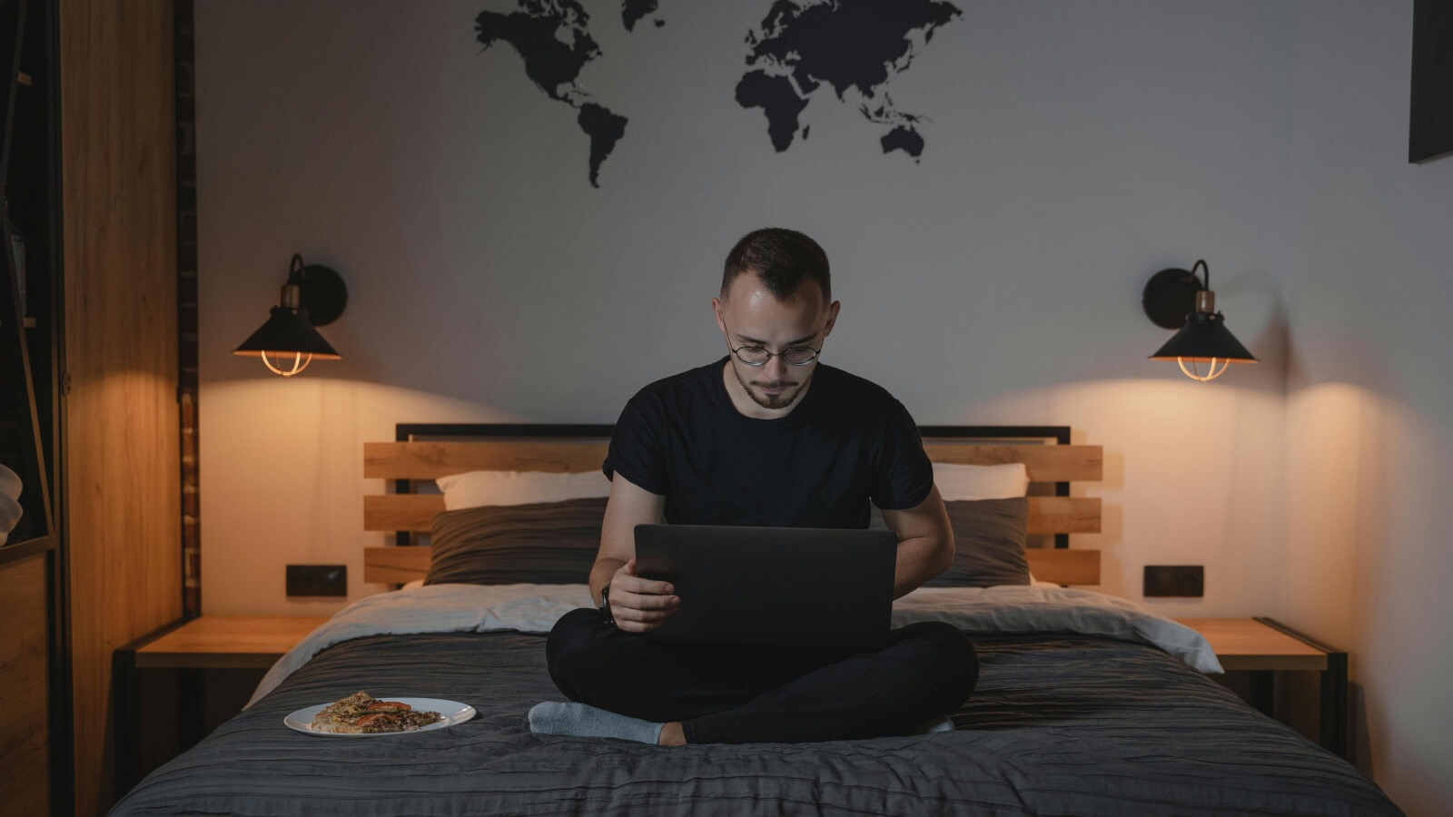 young man sat on his bed working from his laptop