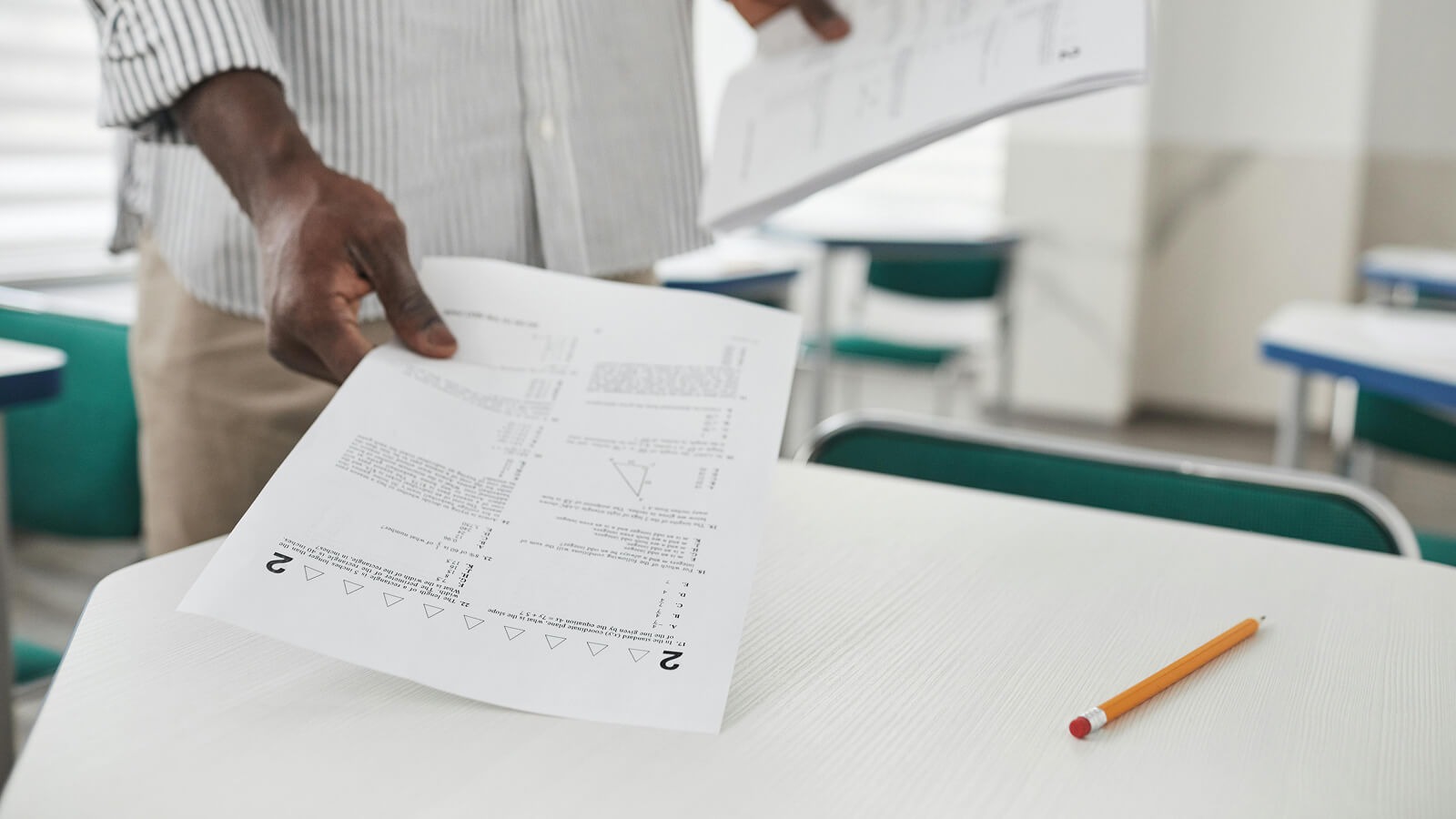 teacher placing differentiated worksheets on a desk