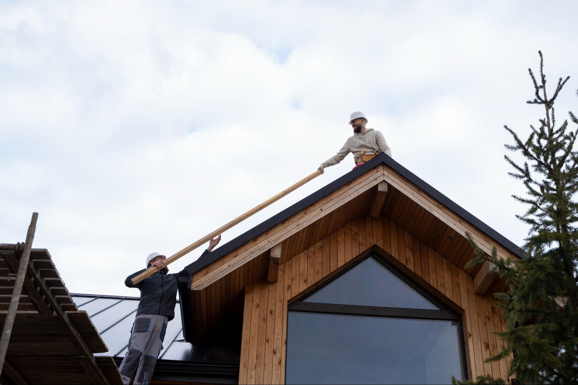 Two construction workers adding a roof over the second storey.