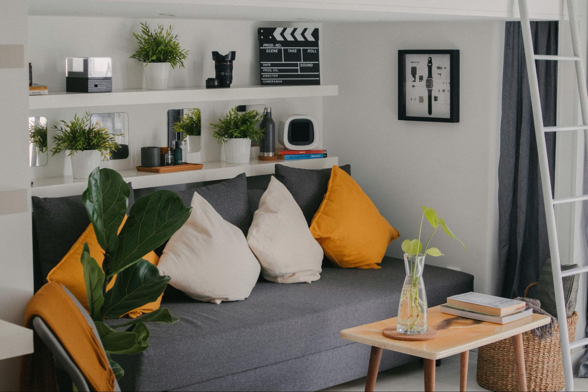 A small living room with a gray couch and floating shelves under renovation.