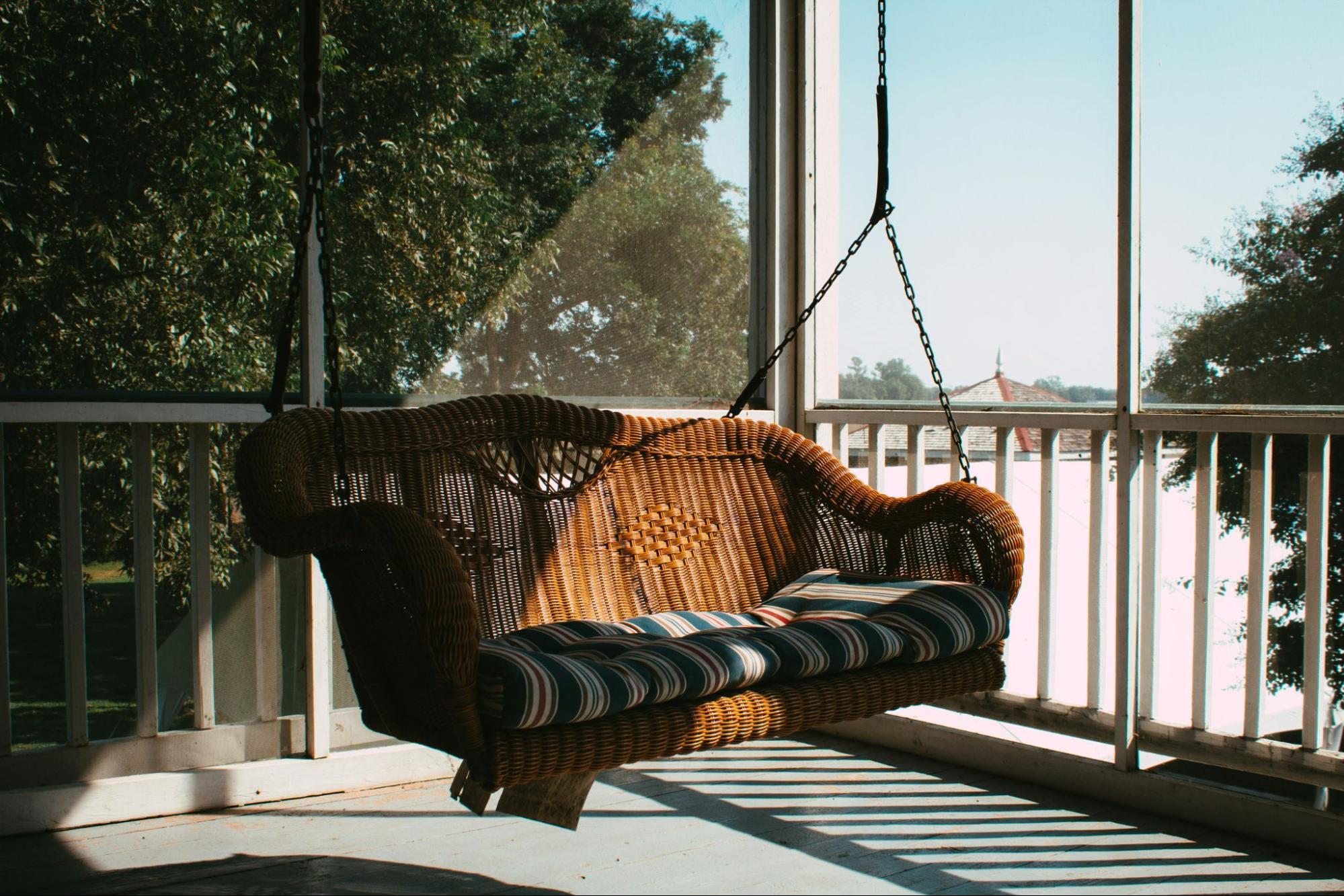 A hanging swing with chains on a porch.