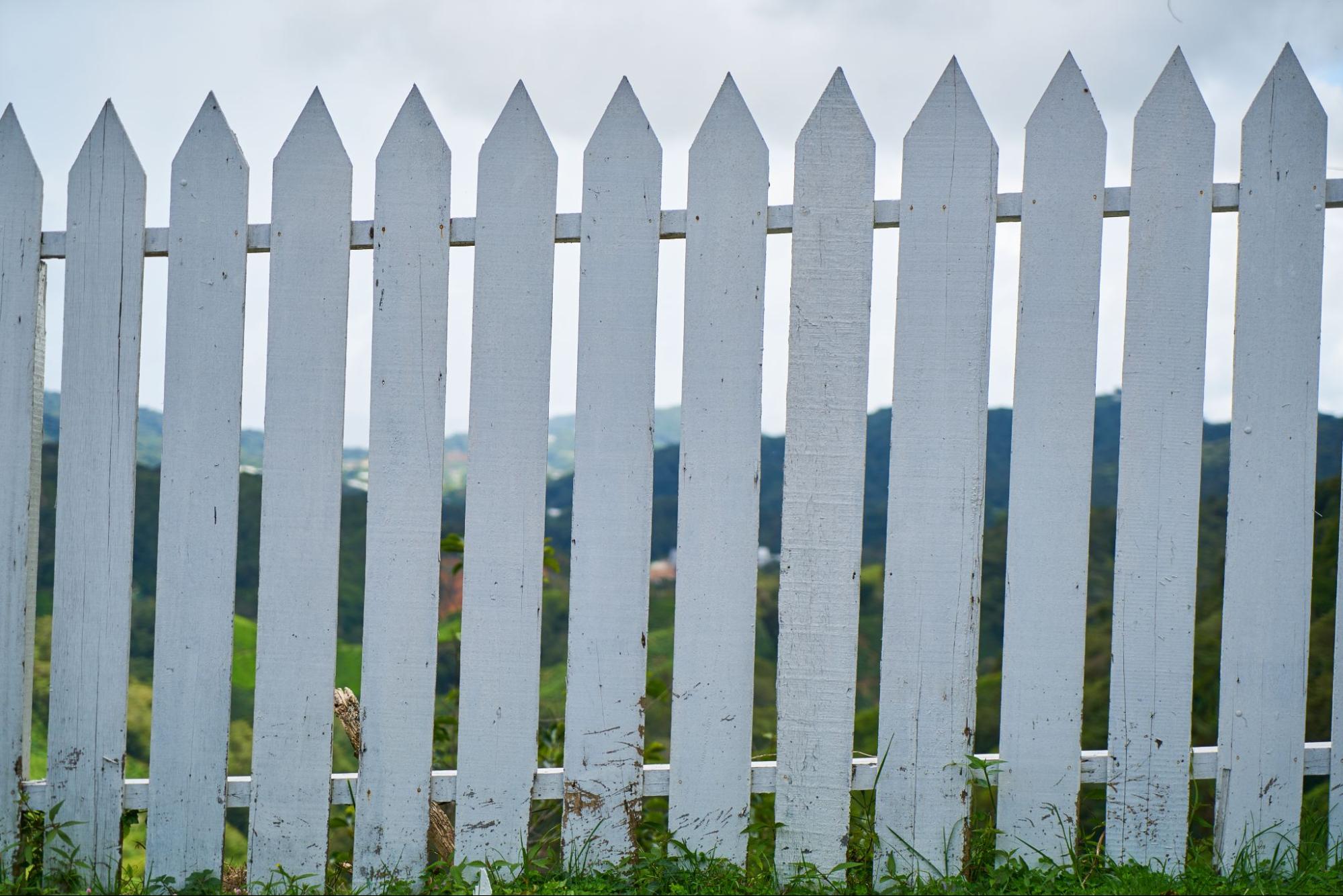 A white picket fence with wooden panels.