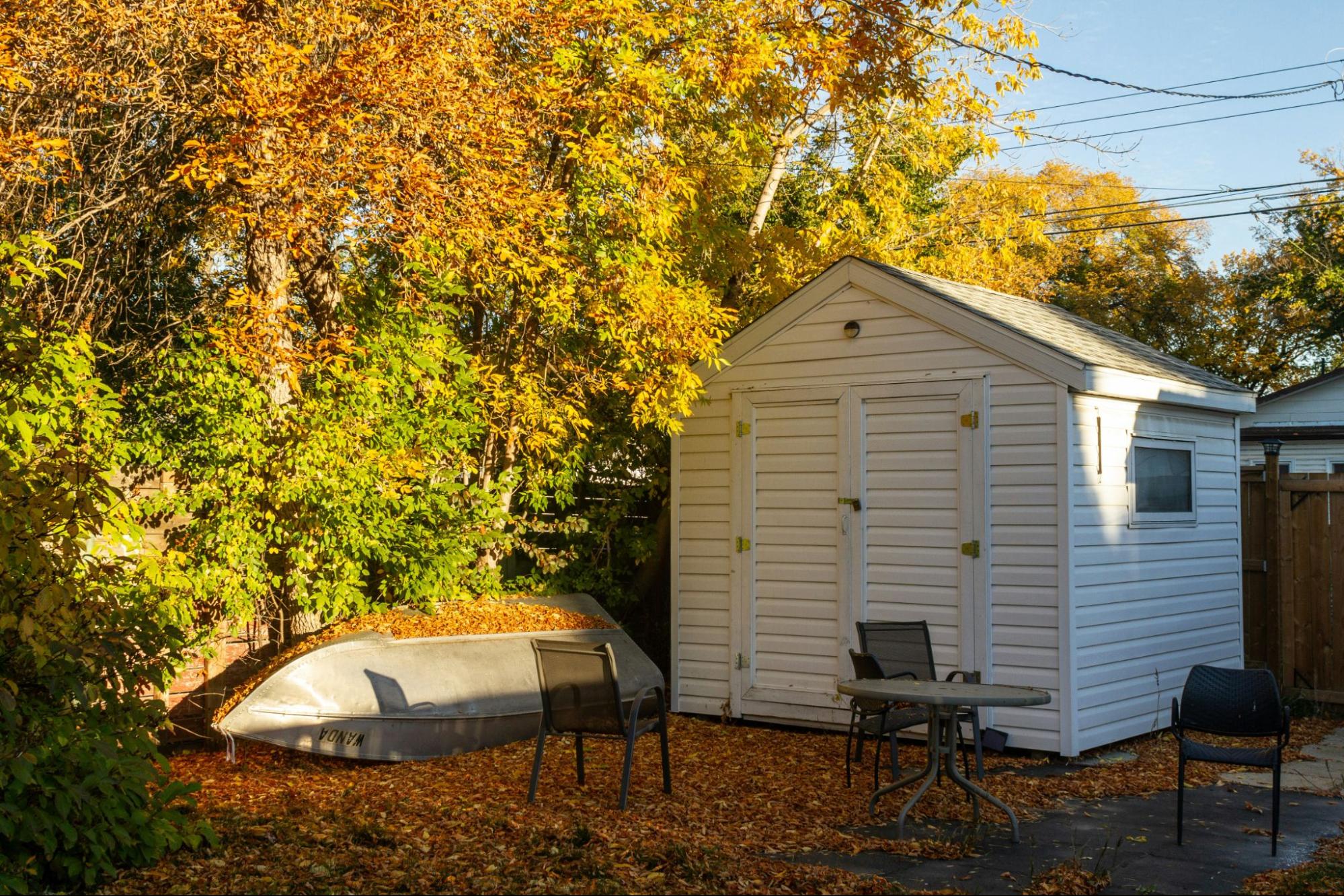 A compact, white wooden shed used for storage.